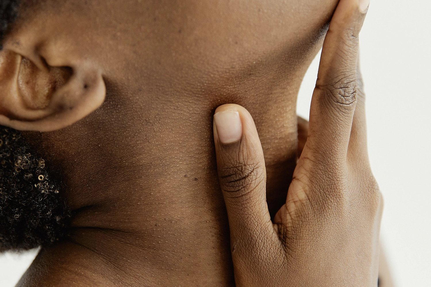 person with head tilted back and hand on throat